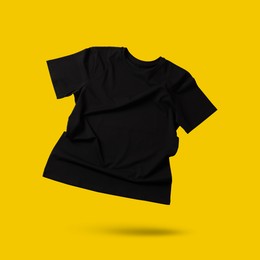 Image of Black t-shirt in air on golden background