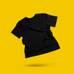 Image of Black t-shirt in air on golden background