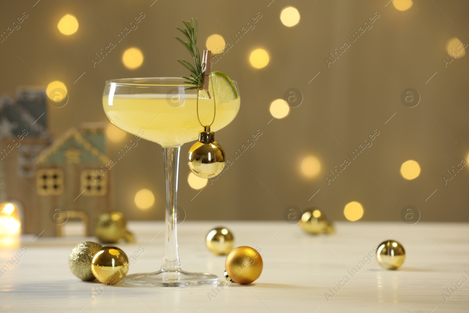 Photo of Tasty Christmas cocktail in glass and decor on white table against dark beige background with blurred lights. Space for text