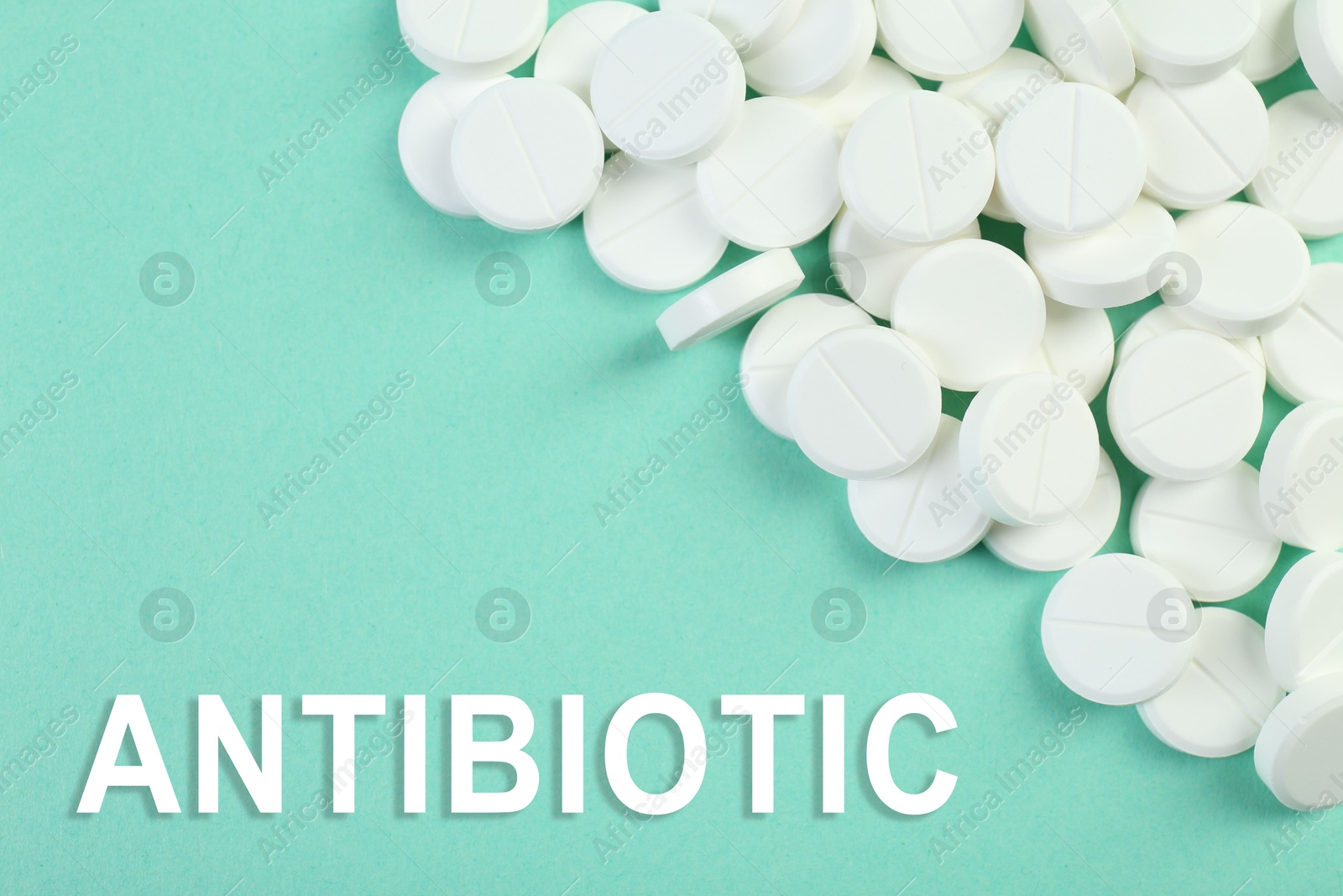 Image of Word Antibiotic and pills on aquamarine color background, top view