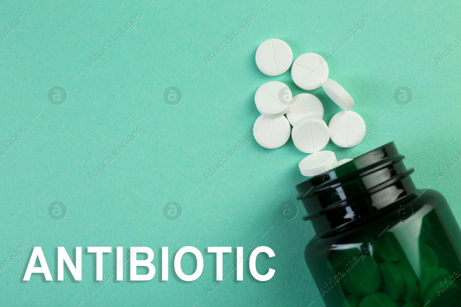 Image of Bottle of antibiotic pills on aquamarine background, top view