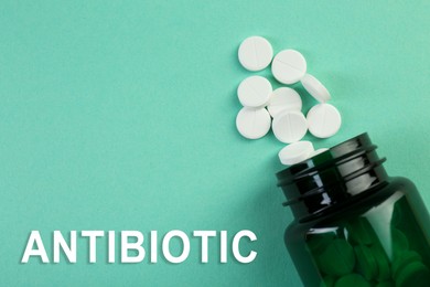 Image of Bottle of antibiotic pills on aquamarine background, top view