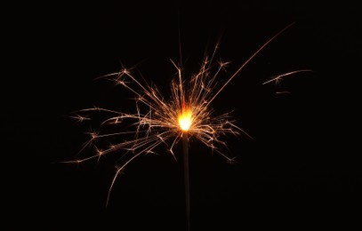 Photo of Burning sparkler stick on black background, space for text