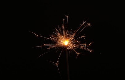 Photo of Burning sparkler stick on black background, space for text