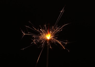 Photo of Burning sparkler stick on black background, space for text