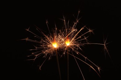 Photo of Burning sparklers glowing in dark, space for text