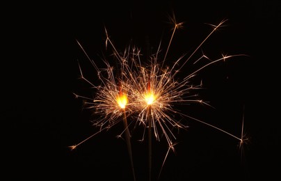 Photo of Burning sparklers glowing in dark, space for text