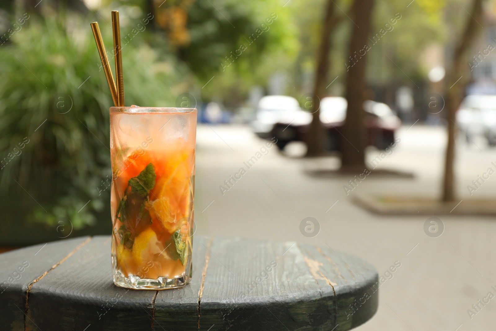 Photo of Glass of tasty refreshing drink and straws on wooden table, space for text