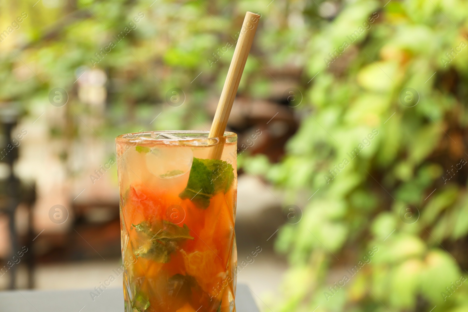 Photo of Glass of tasty refreshing drink and straw outdoors, closeup