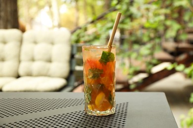 Photo of Glass of tasty refreshing drink and straw on table in outdoor cafe