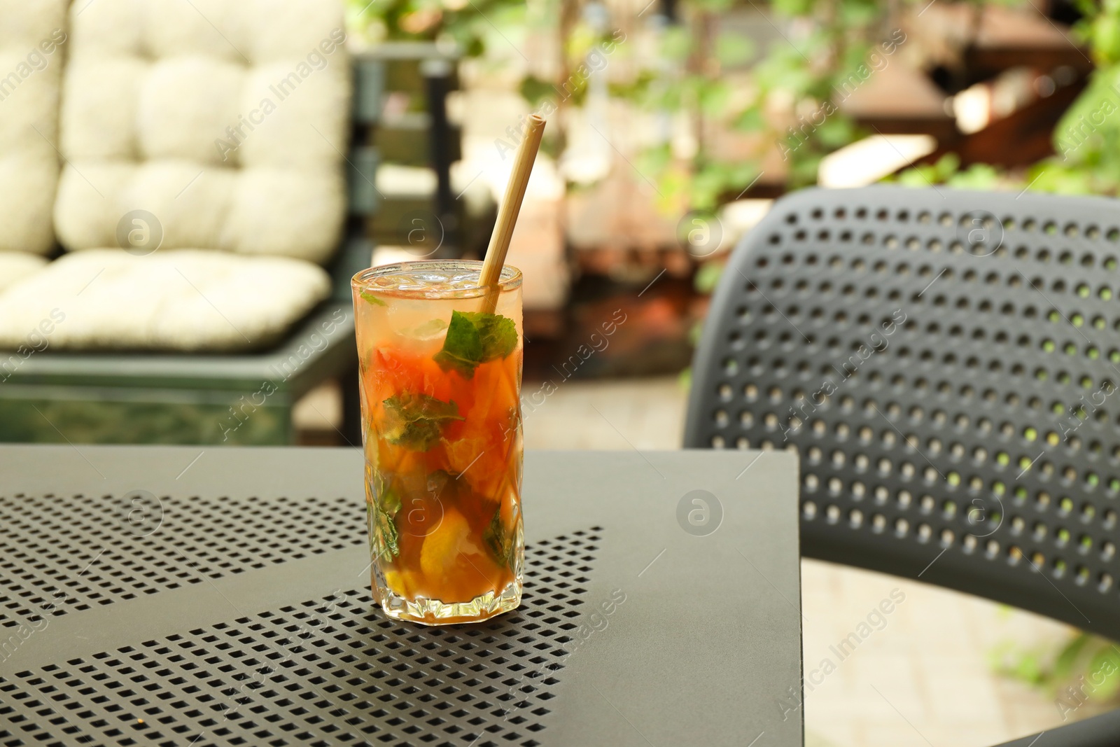 Photo of Glass of tasty refreshing drink and straw on table in outdoor cafe