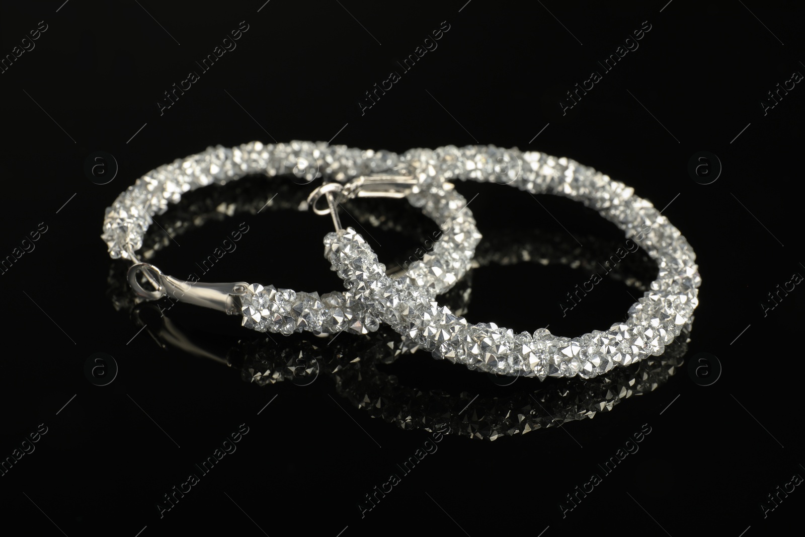 Photo of Beautiful bijouterie. Stylish earrings on black background