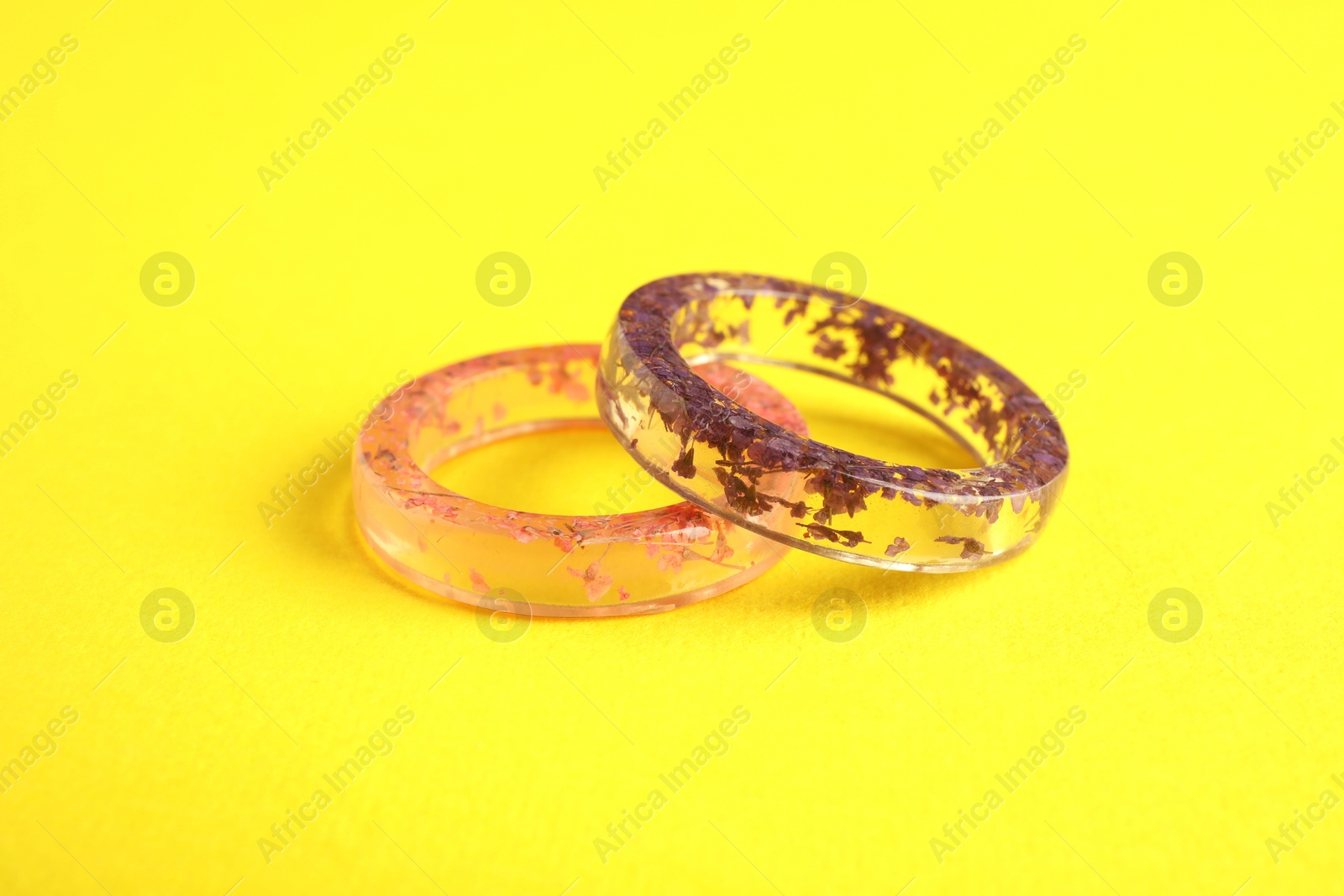 Photo of Beautiful bijouterie. Elegant rings on yellow background, closeup