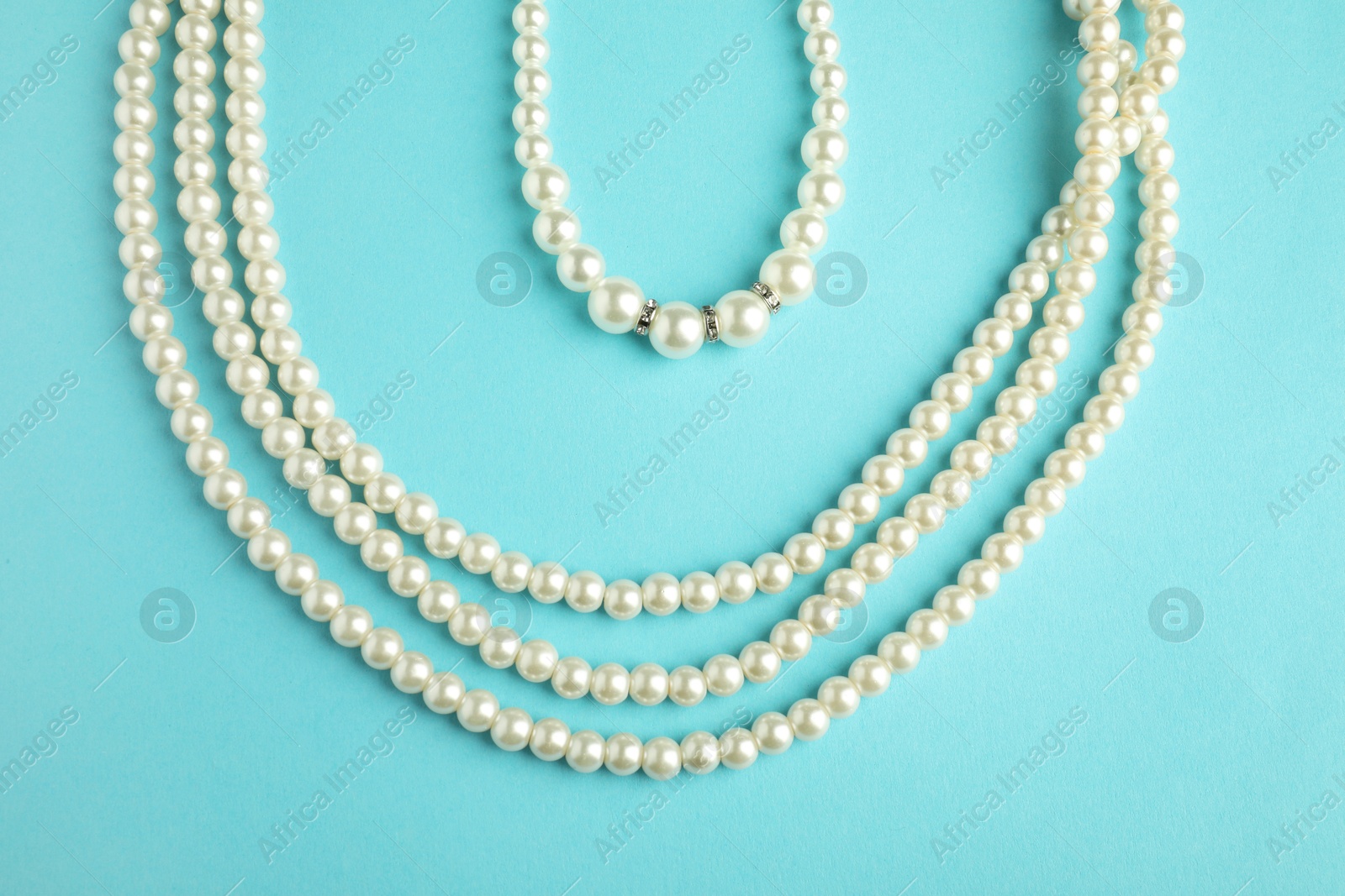 Photo of Beautiful bijouterie. Stylish necklace and bracelet on light blue background, top view