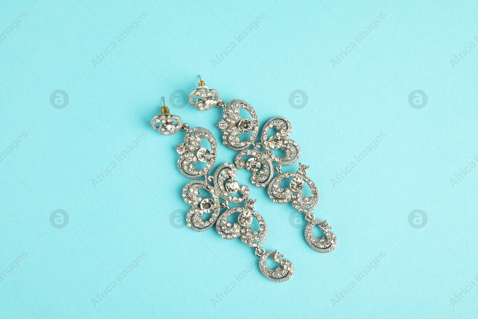 Photo of Beautiful bijouterie. Stylish earrings on light blue background, top view