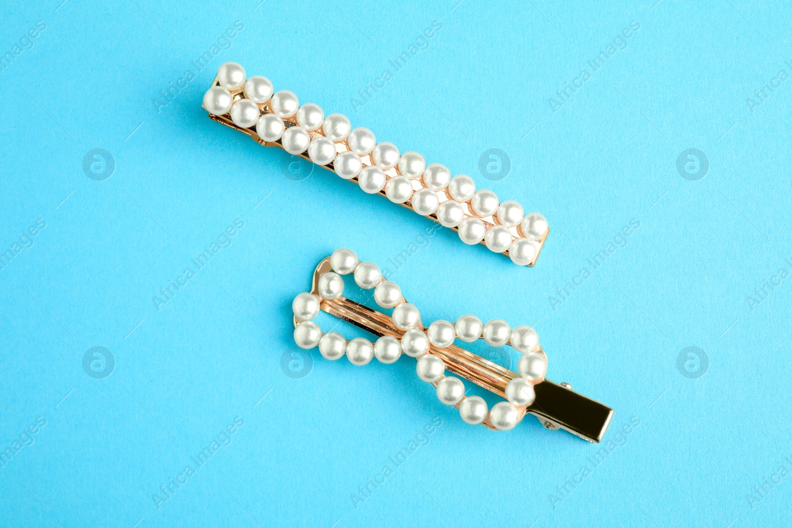 Photo of Beautiful bijouterie. Elegant hair clips on light blue background, top view