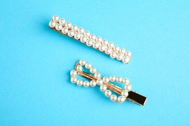 Beautiful bijouterie. Elegant hair clips on light blue background, top view