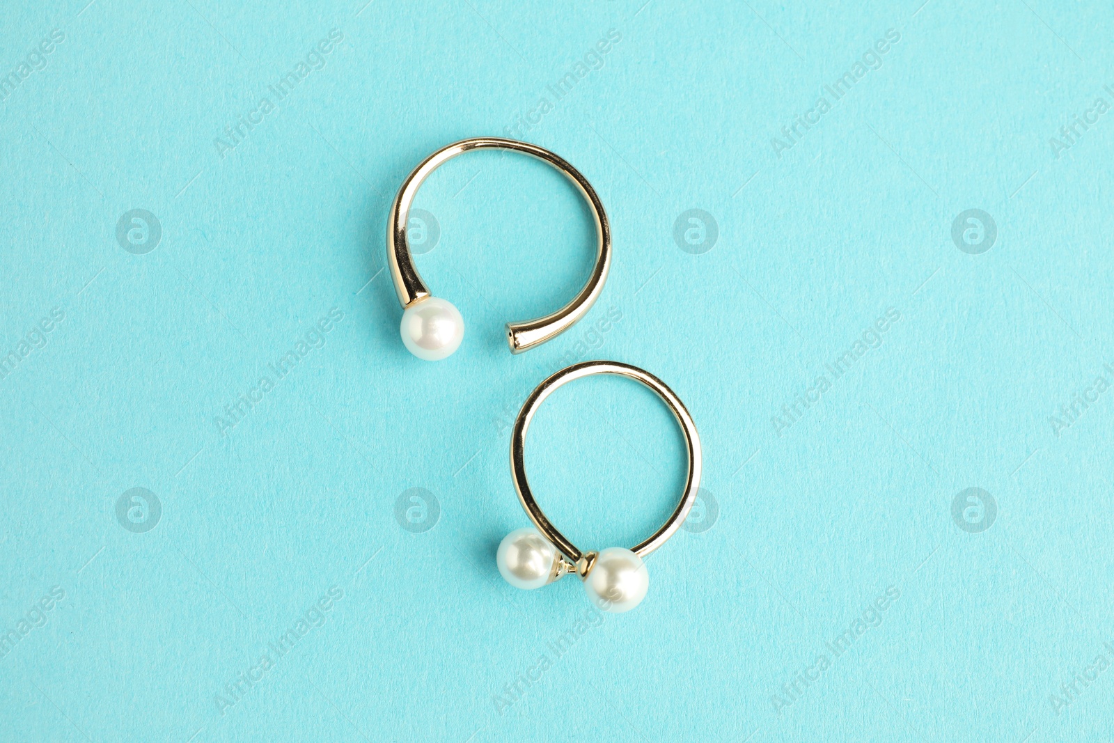 Photo of Beautiful bijouterie. Stylish rings on light blue background, top view