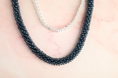 Photo of Beautiful bijouterie. Stylish necklace and bracelet on light pink background, top view