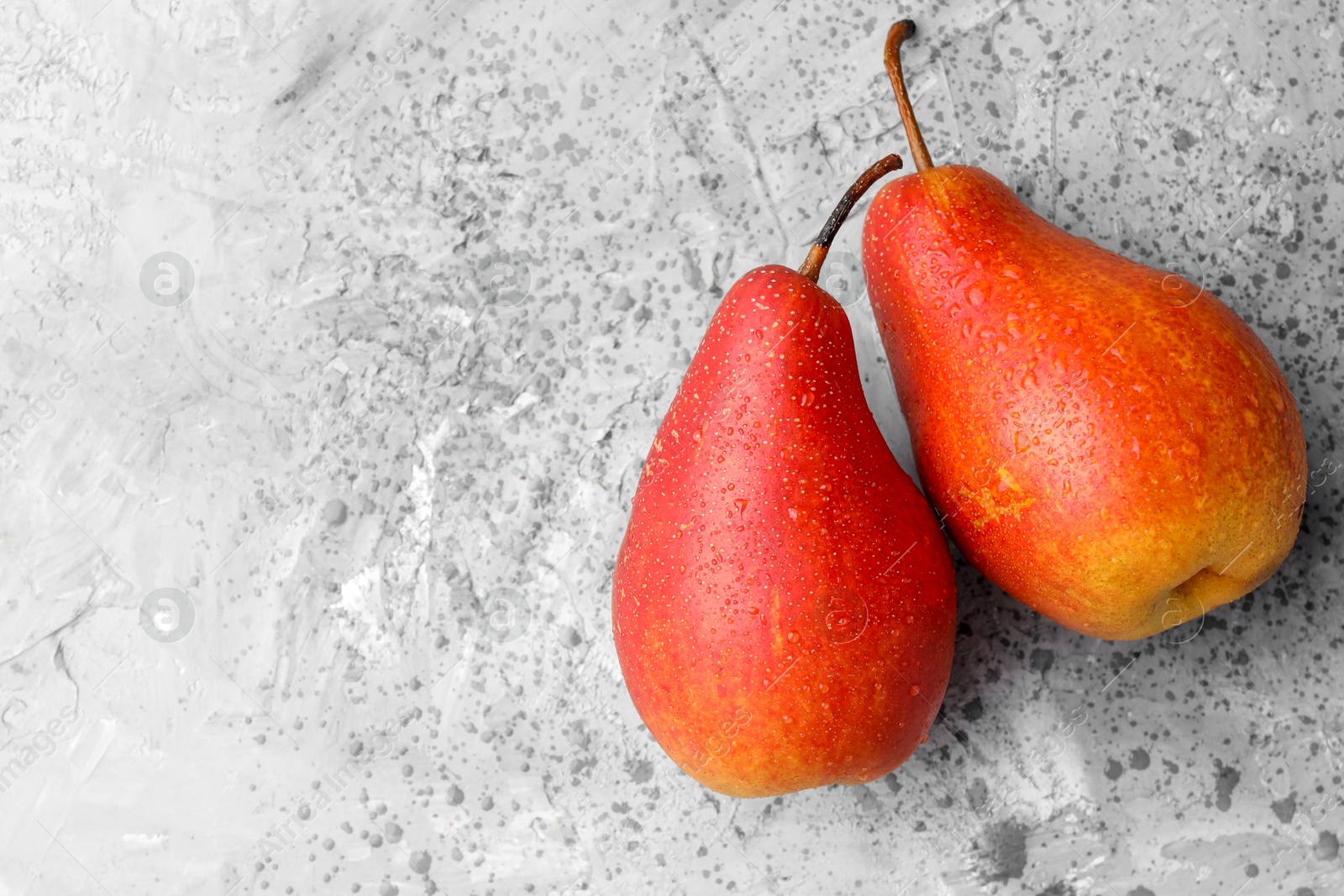 Photo of Two ripe juicy pears on grey table, top view. Space for text