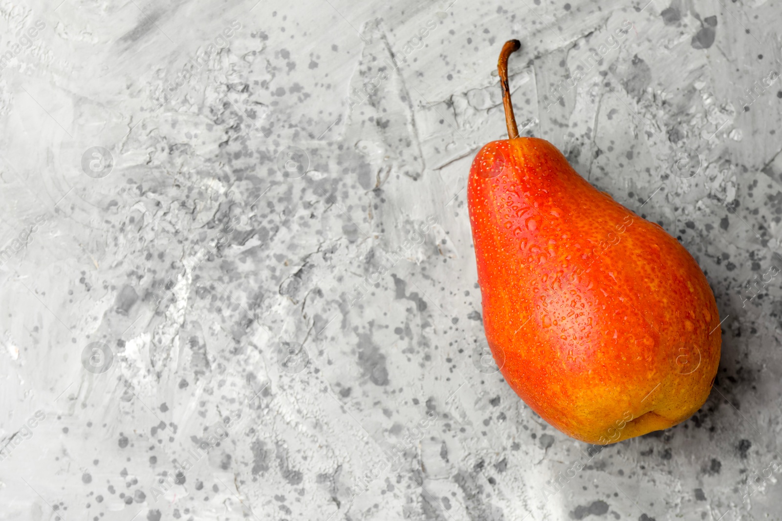 Photo of One ripe juicy pear on grey table, top view. Space for text