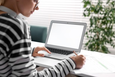 Photo of Woman working at table with laptop in office, closeup. Mockup for design