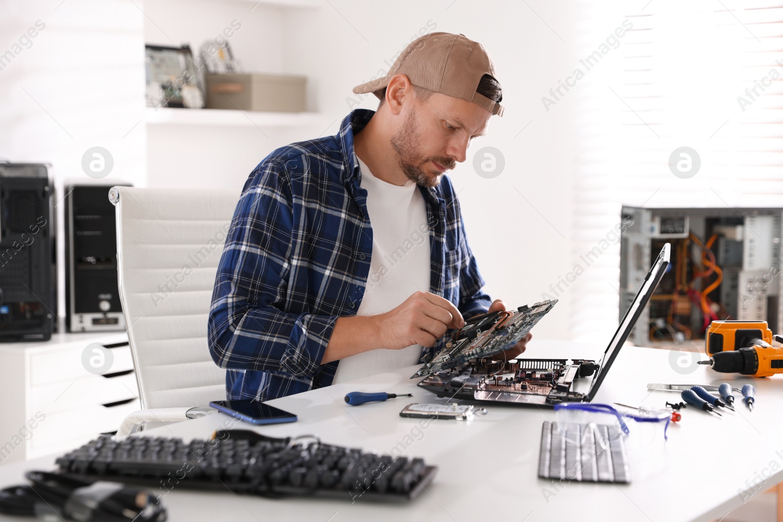 Photo of Man installing motherboard into laptop at white table