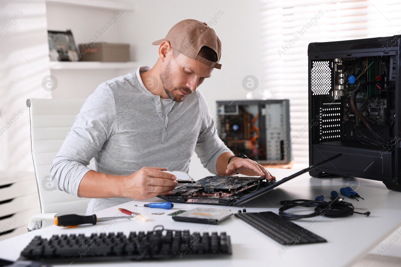 Photo of Man fixing old laptop at white table