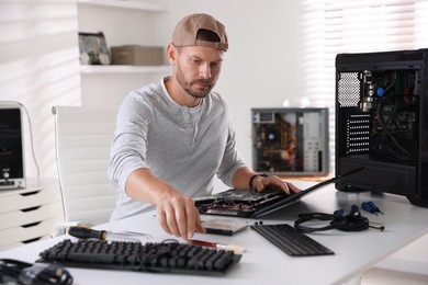 Photo of Man fixing old laptop at white table