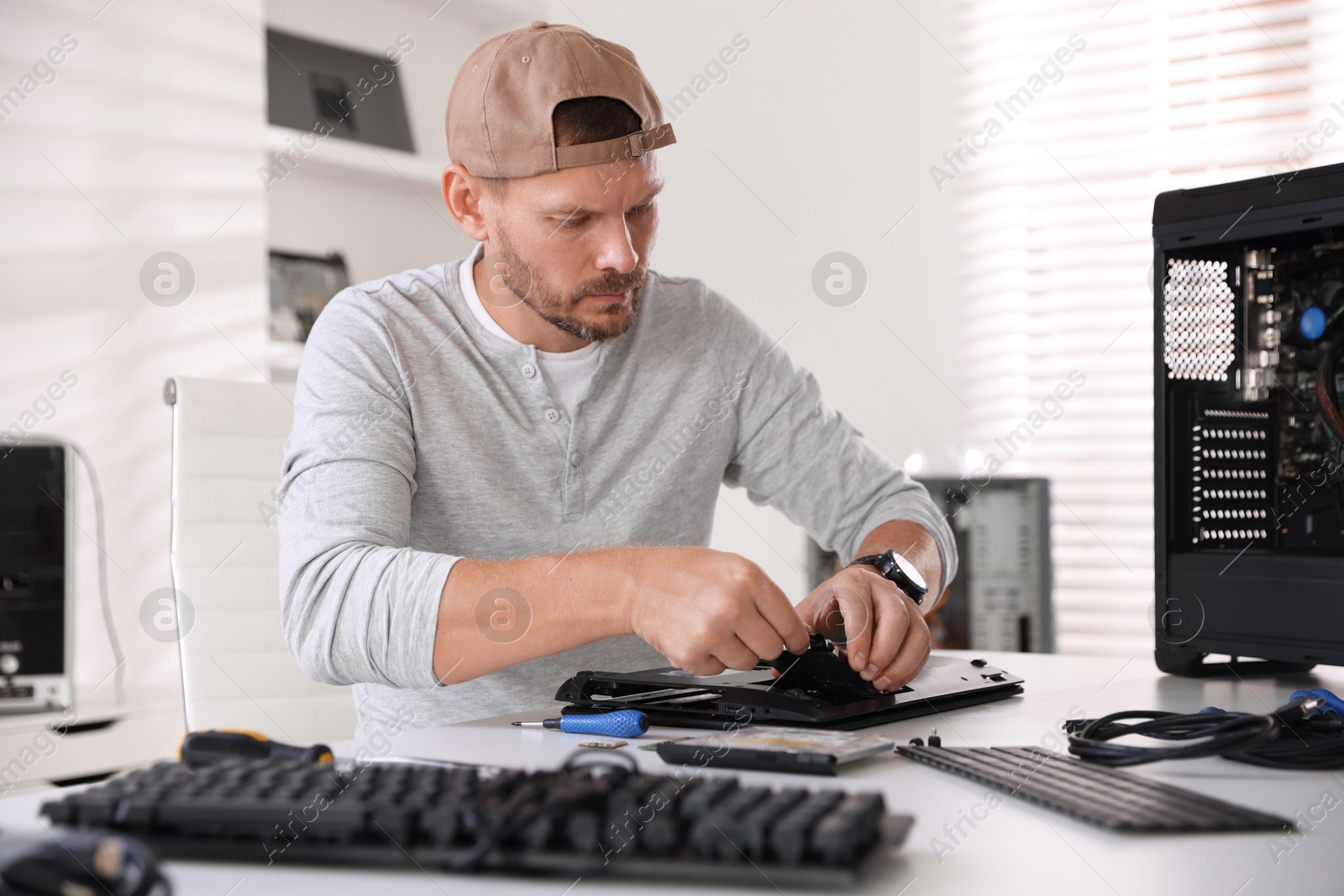 Photo of Man fixing old laptop at white table