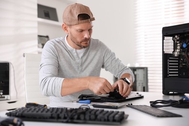 Photo of Man fixing old laptop at white table