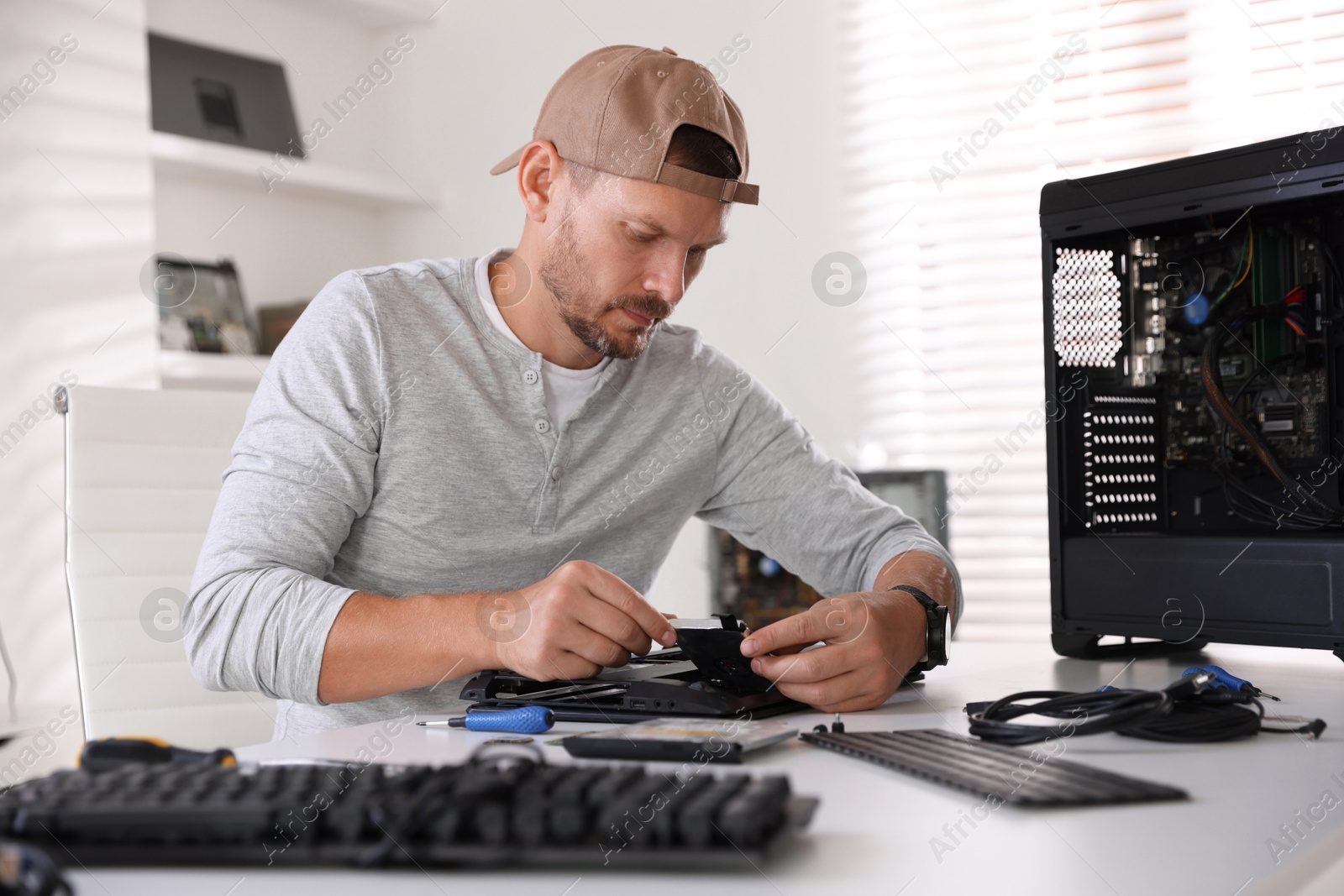 Photo of Man fixing old laptop at white table