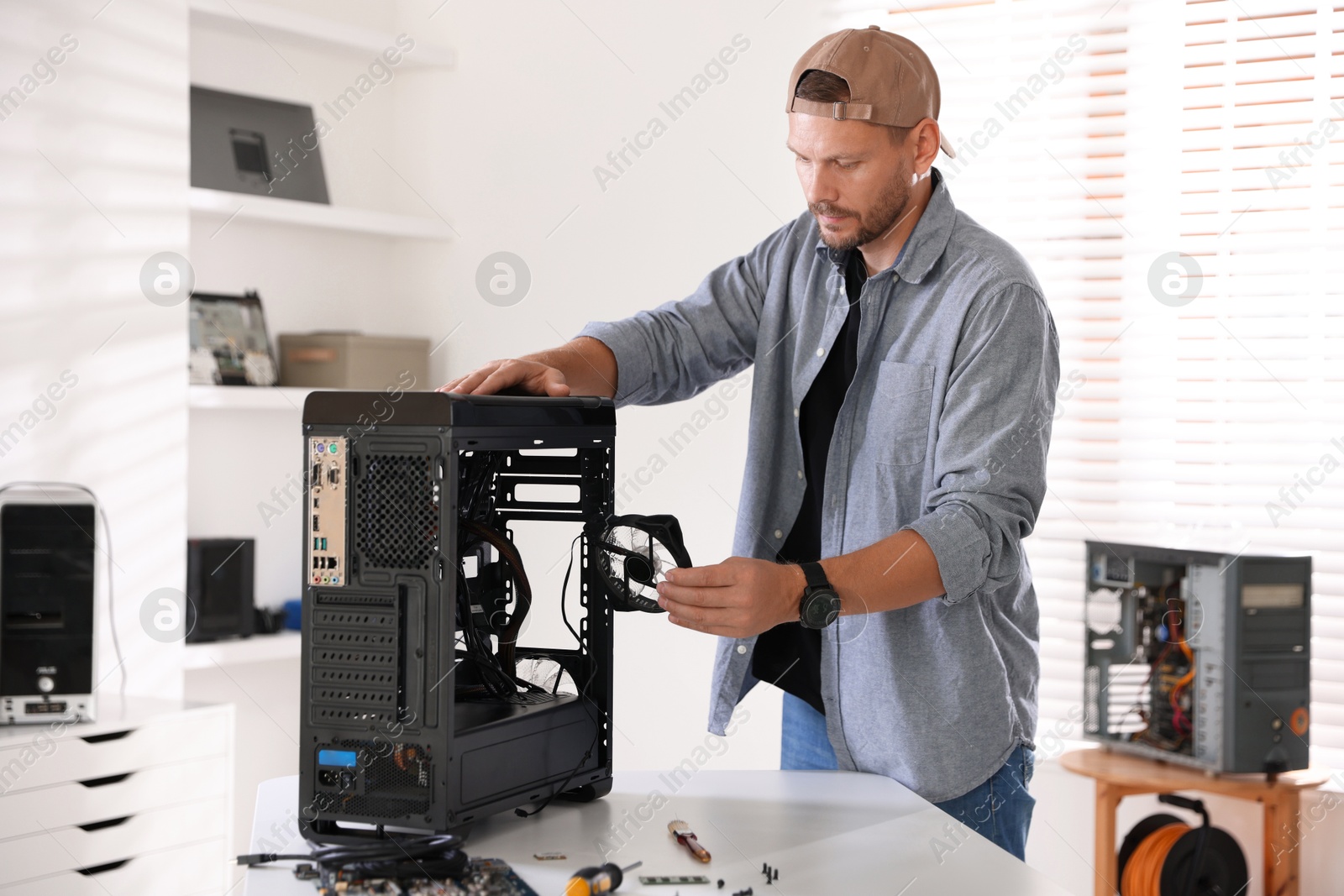 Photo of Man installing fan into computer at white table