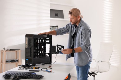 Photo of Man installing fan into computer at white table