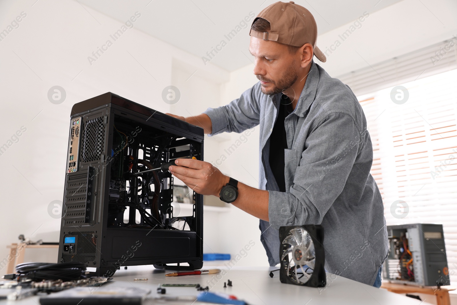 Photo of Man installing fan into computer at white table