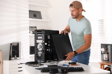 Photo of Man assembling new computer at white table