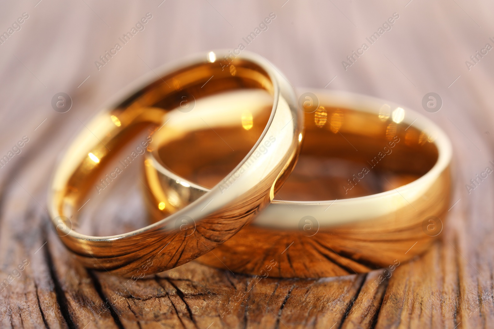 Photo of Beautiful golden wedding rings on wooden background, closeup