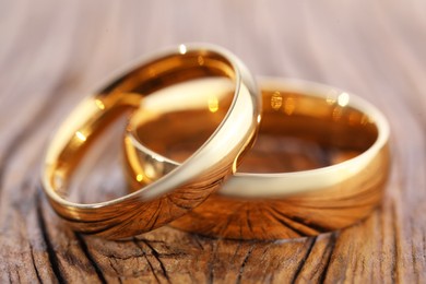 Photo of Beautiful golden wedding rings on wooden background, closeup