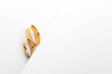 Photo of Beautiful golden wedding rings on white background, space for text