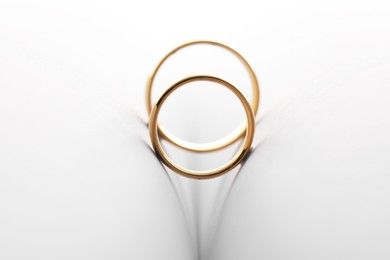 Photo of Beautiful golden wedding rings on light background, closeup