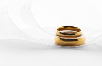 Beautiful golden wedding rings and ribbon on white background