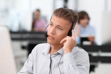 Photo of Salesman talking to client via headset in office