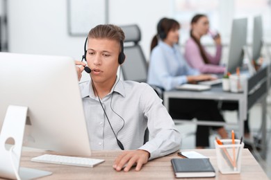 Salesman talking to client via headset at desk in office