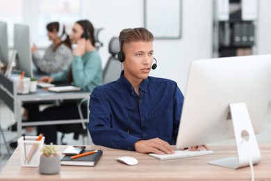 Photo of Salesman talking to client via headset at desk in office