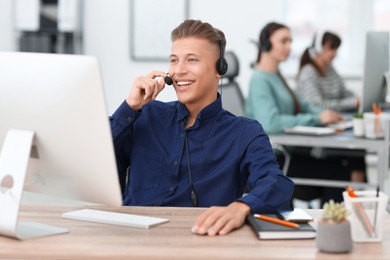 Photo of Salesman talking to client via headset at desk in office