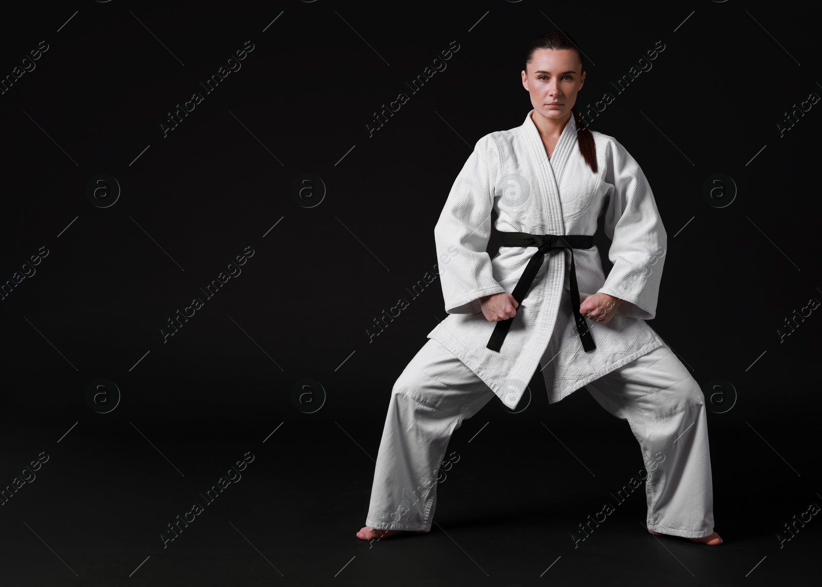 Photo of Karate fighter in kimono on black background, space for text