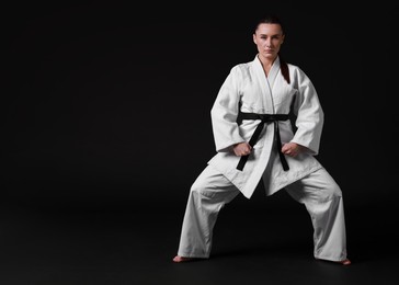 Photo of Karate fighter in kimono on black background, space for text