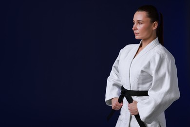 Karate fighter in kimono on dark background, space for text