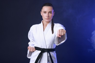 Photo of Karate fighter in kimono on dark blue background