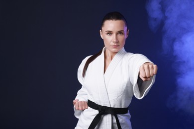 Photo of Karate fighter in kimono on dark blue background